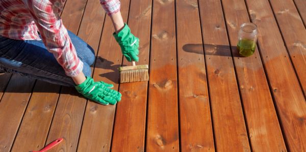 DIYer applying the first coat of pure tung oil on deck boards