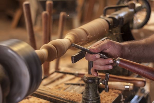  a man doing wood turning using a skew chisel with wood shavings around