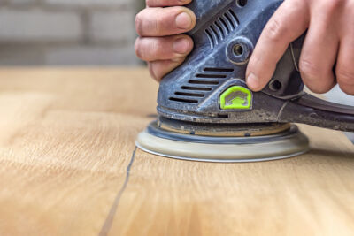 a man sanding wood, opening the pores to pickle wood with milk paint